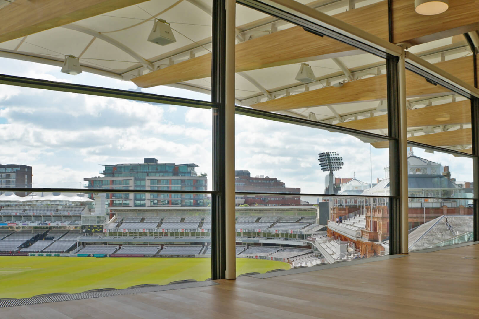 Vue intérieure à travers le vitrage à guillotine de la tribune Warner vers le terrain de cricket.